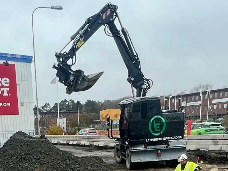 Svart hjulgrävare med Leons-logotyp vid en schaktmassa