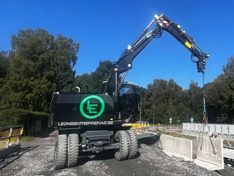 Svart hjulgrävare med Leons-logotyp och lyftkätting vid vägbygge