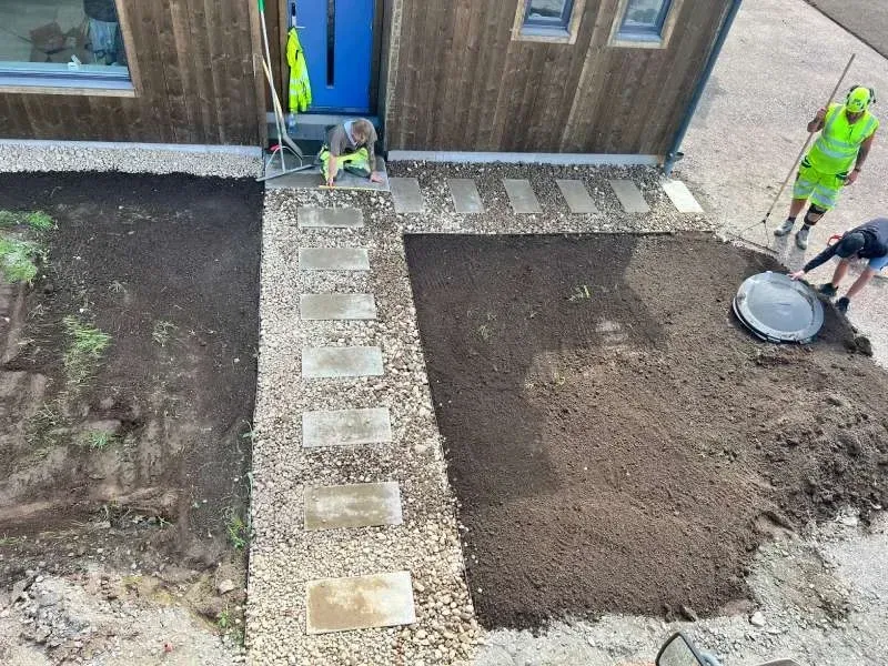 Gångväg av stenplattor i grus framför ett hus, under arbete