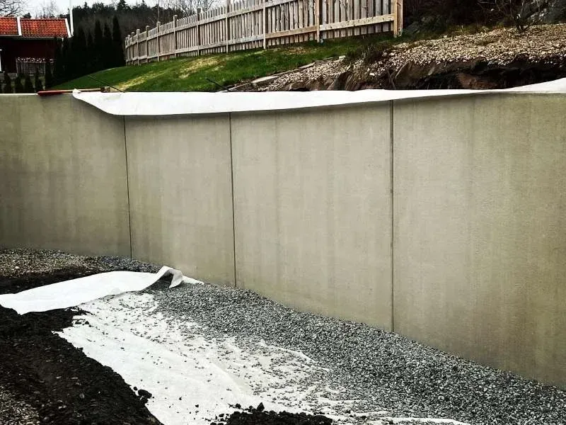 Stödmur av betongelement med grus och markduk framför